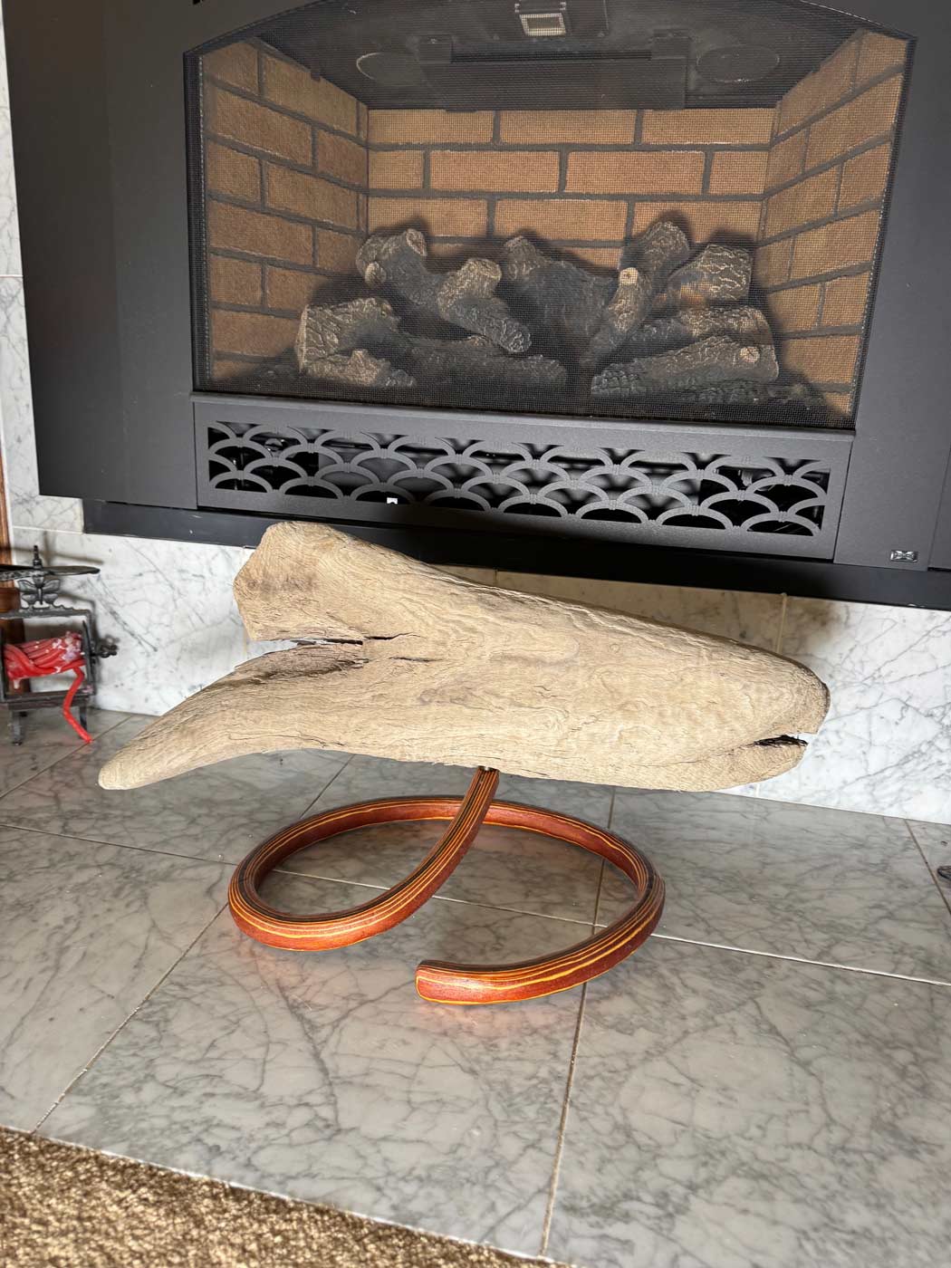 Wooden sculpture on a stand in front of a fireplace with bricks