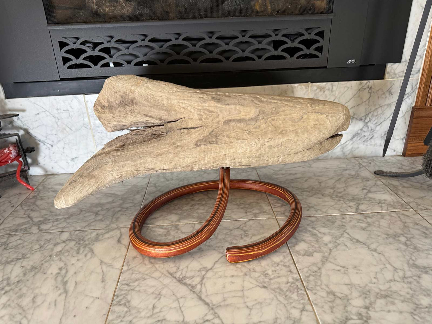 Wooden sculpture on a marble floor with a fireplace in the background